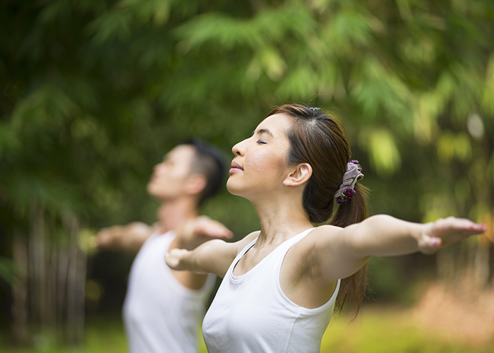 Asian Man and woman doing Tai Chi in a garden. Healthy lifestyle and relaxation concept.